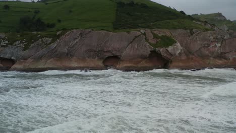 Itzurun-beach-sea-caves-on-Zumaia-spain-coast-as-waves-crash-in-slow-motion