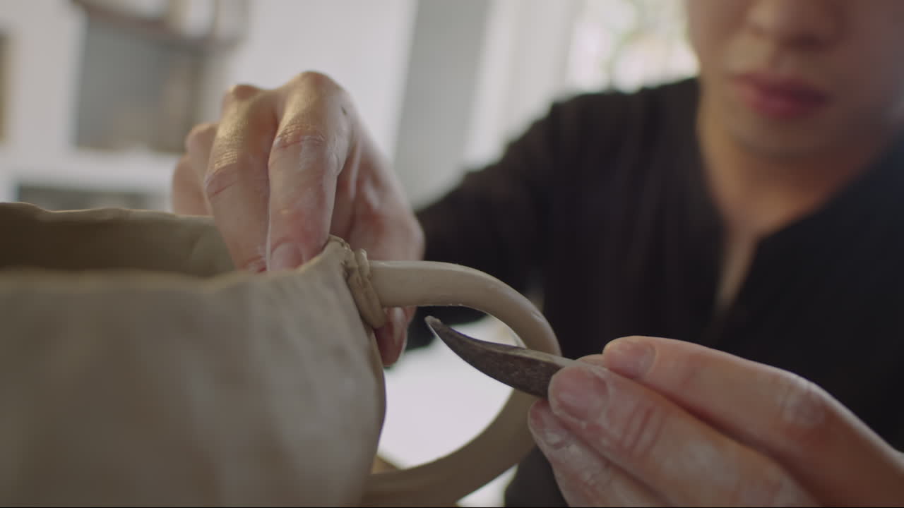 Ceramist Attaching Handle to Mug with Potter Rib