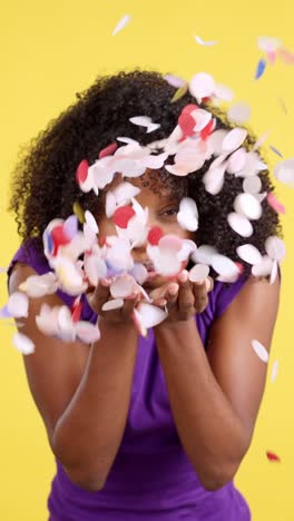 young woman blowing colorful heart confetti