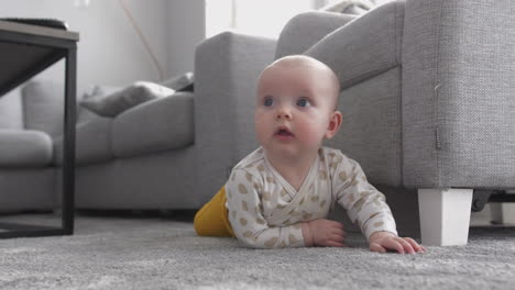 caucasian toddler turns on to front on living room carpet