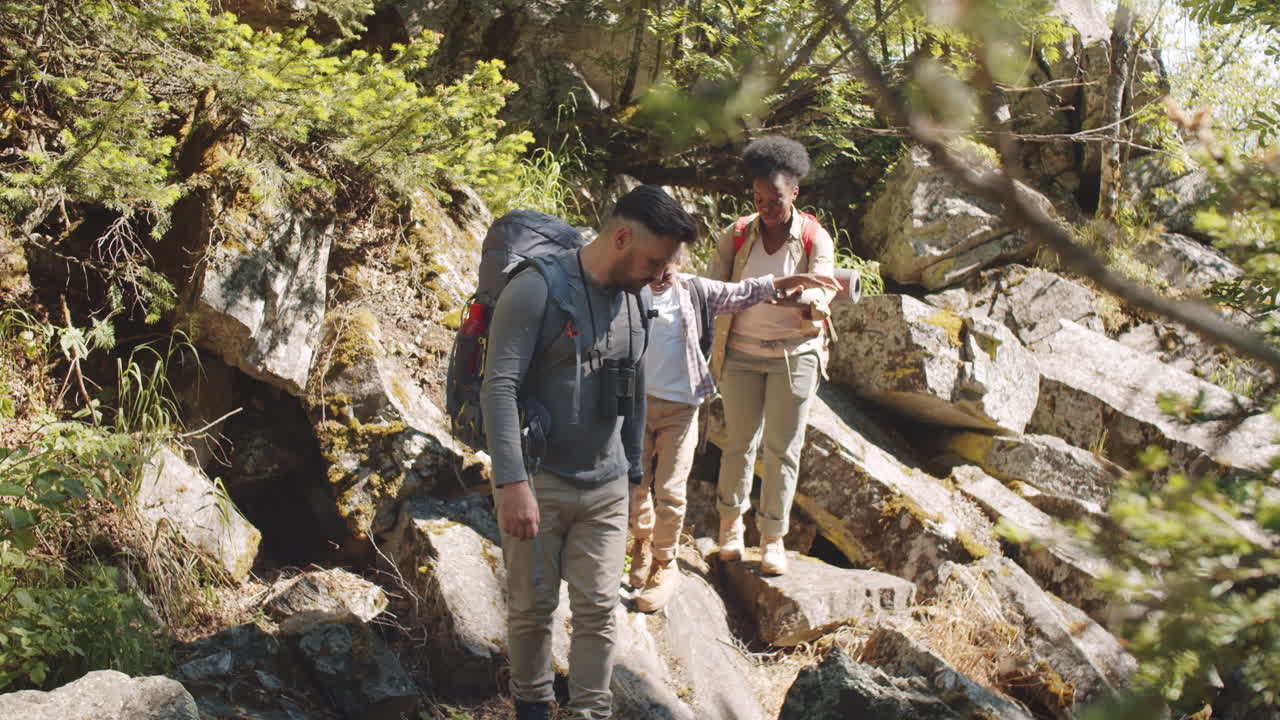 familia multiétnica caminando por un sendero rocoso durante una caminata