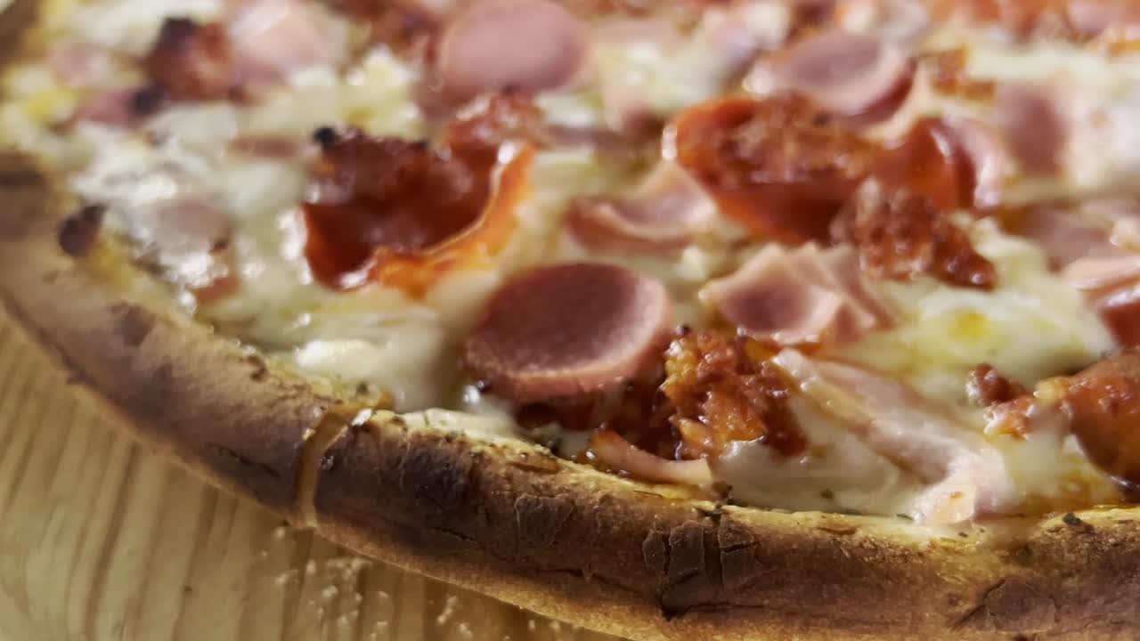 Primo piano di pizza con prosciutto, formaggio e crosta, ripresa a mano libera