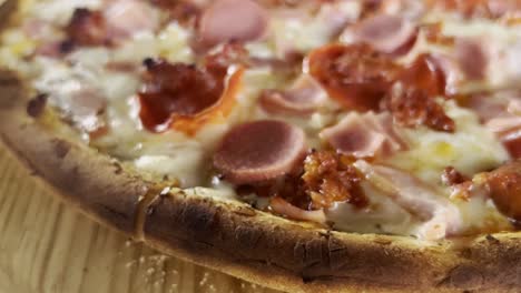 fotografía de cerca de una pizza con jamón, queso y corteza, de mano