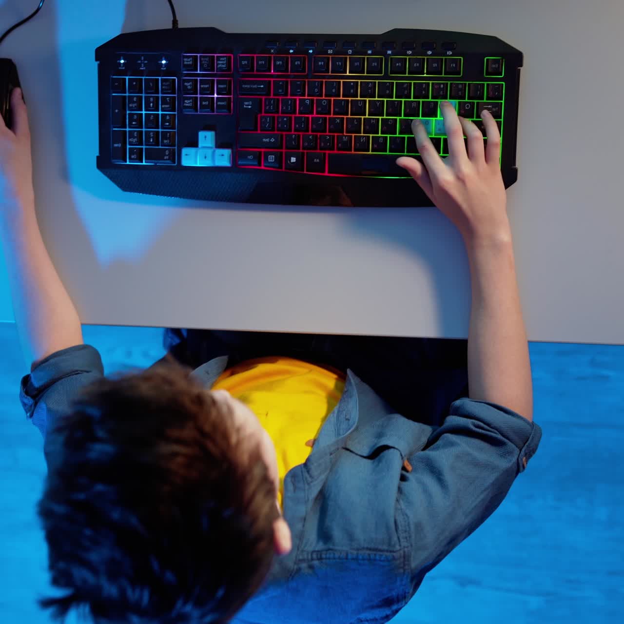 Boy plays video games. Modern keyboard on the desk. Amazed boy looking up and standing. Games at home. Top view.