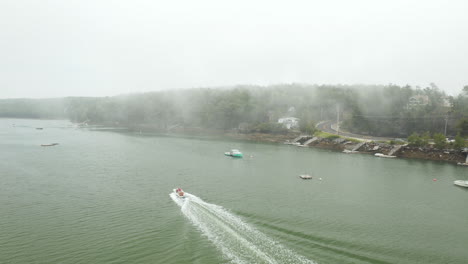 Sobrevolar-Imágenes-Aéreas-De-Drones-Sobre-La-Costa-De-Harpswell,-Condado-De-Cumberland,-Maine,-Que-Muestra-Una-Lancha-Rápida-Cruzando-El-Agua-Paralela-A-La-Costa-En-Un-Día-Nublado