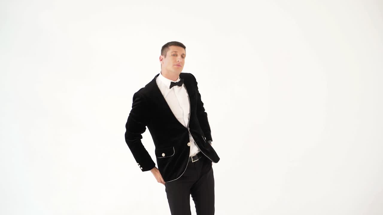 funny man in a black suit and white shirt is dancing macarena on the background of white studio. Parody of the popular dance. Macarena