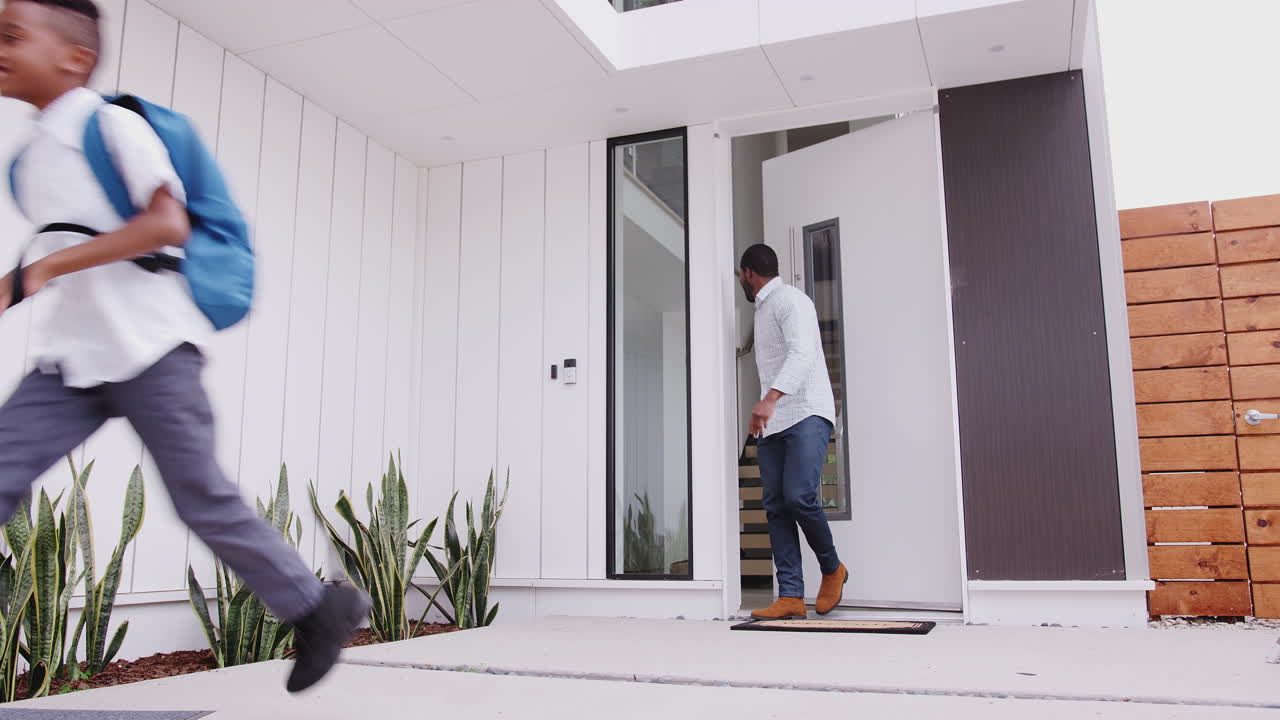 Excited Children Running Out Of Front Door On Way To School Watched By Father