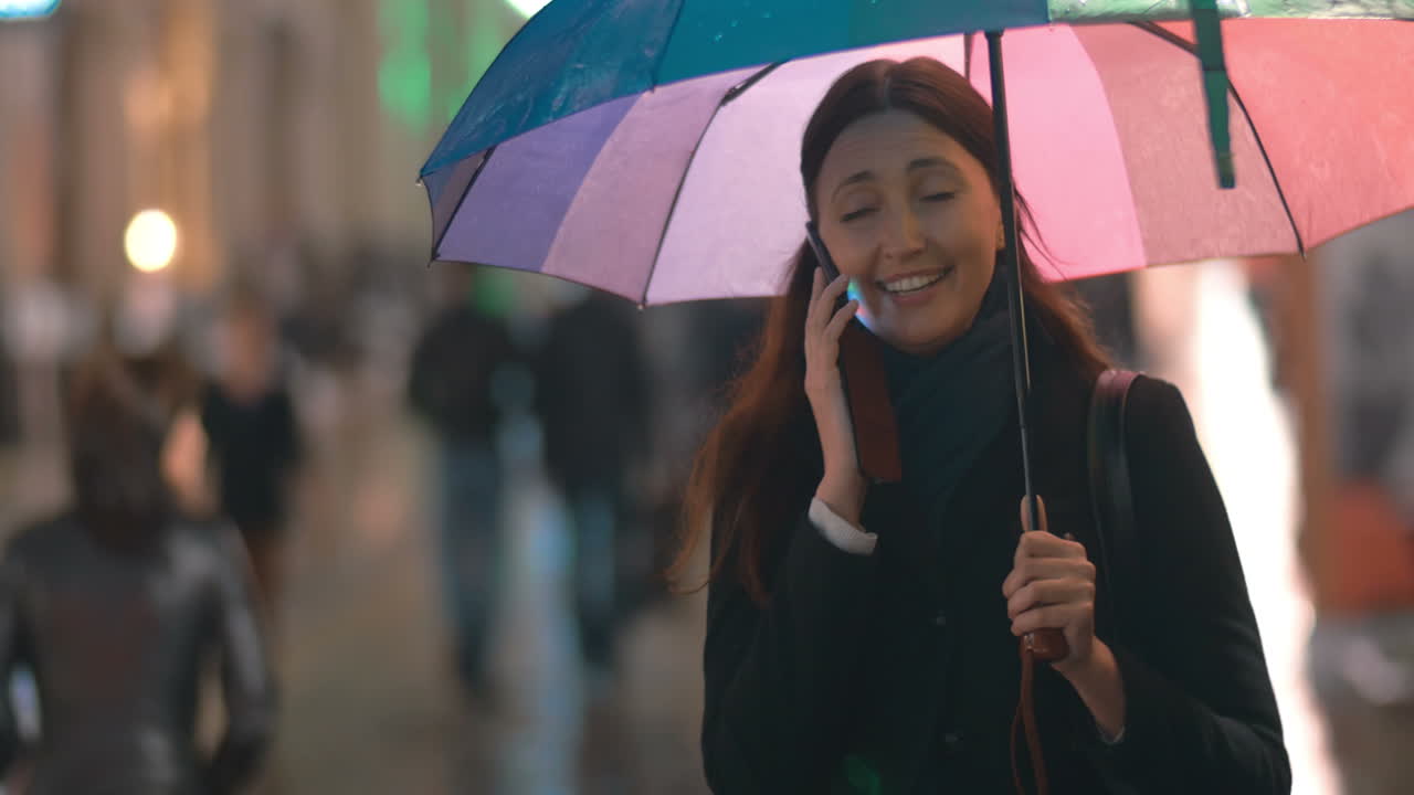 Giovane donna con l'ombrello che parla al telefono