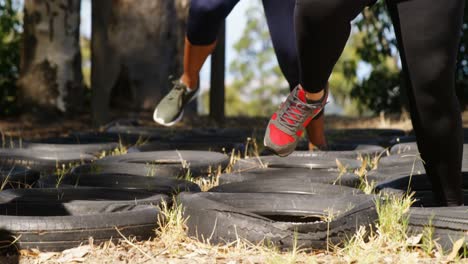 Sección-Baja-De-Mujeres-Corriendo-Sobre-Neumáticos-Durante-La-Carrera-De-Obstáculos