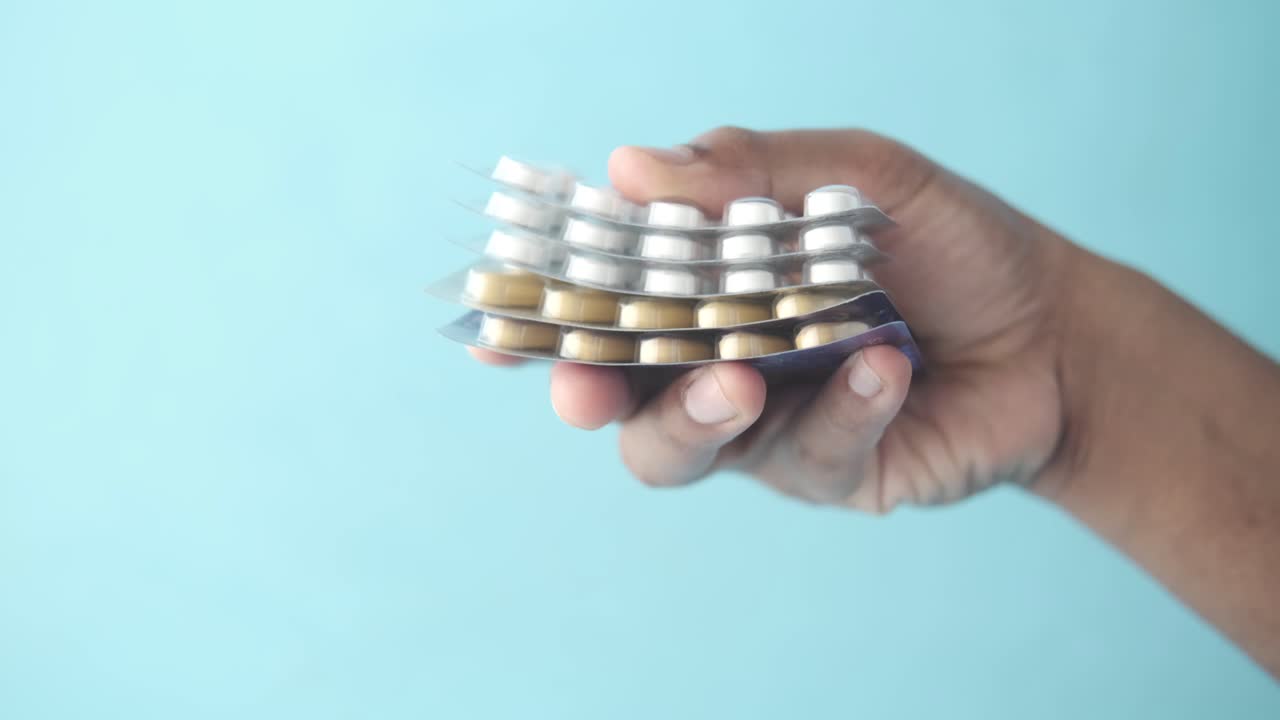 손은 블리스터 패키지에있는 약물 태블릿과 을 고 있습니다.