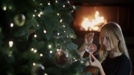 The-girl-is-sitting-near-a-beautiful-Christmas-tree,-holding-a-toy-in-her-hands.-Preparing-to-celebrate-Christmas