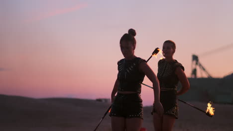 fire dancers against sunset. a young woman poses with her fire hoop against the sunset during her dance performance