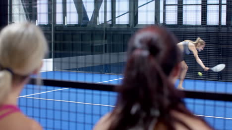 smiling woman in sportswear playing padel tennis indoors, enjoying game, at indoor court