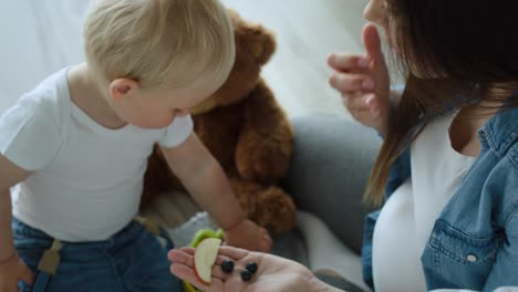 handheld video of toddler feeding mother with fresh fruits.