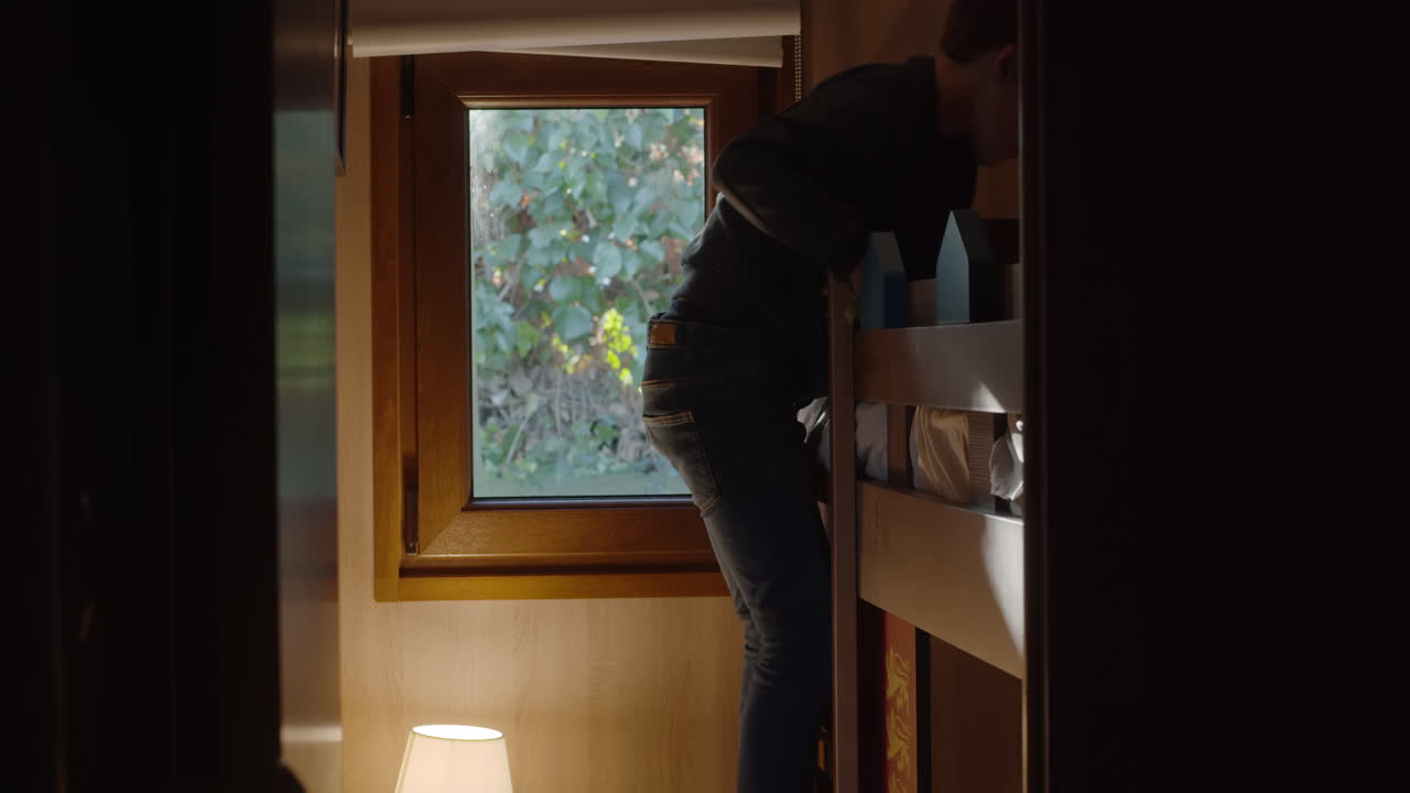 두 층 침대의 사다리를 내려오는 소년