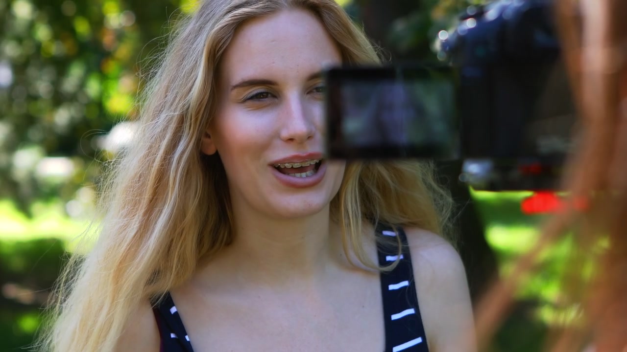 Una vlogger bionda che registra il pubblico per il suo vlog con un amico che tiene la telecamera. Racconta della sua passione.