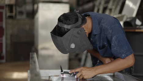 a person welding metal with a welding mask in a workshop