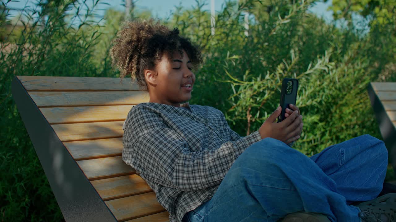 Femme utilisant son téléphone sur un banc de parc