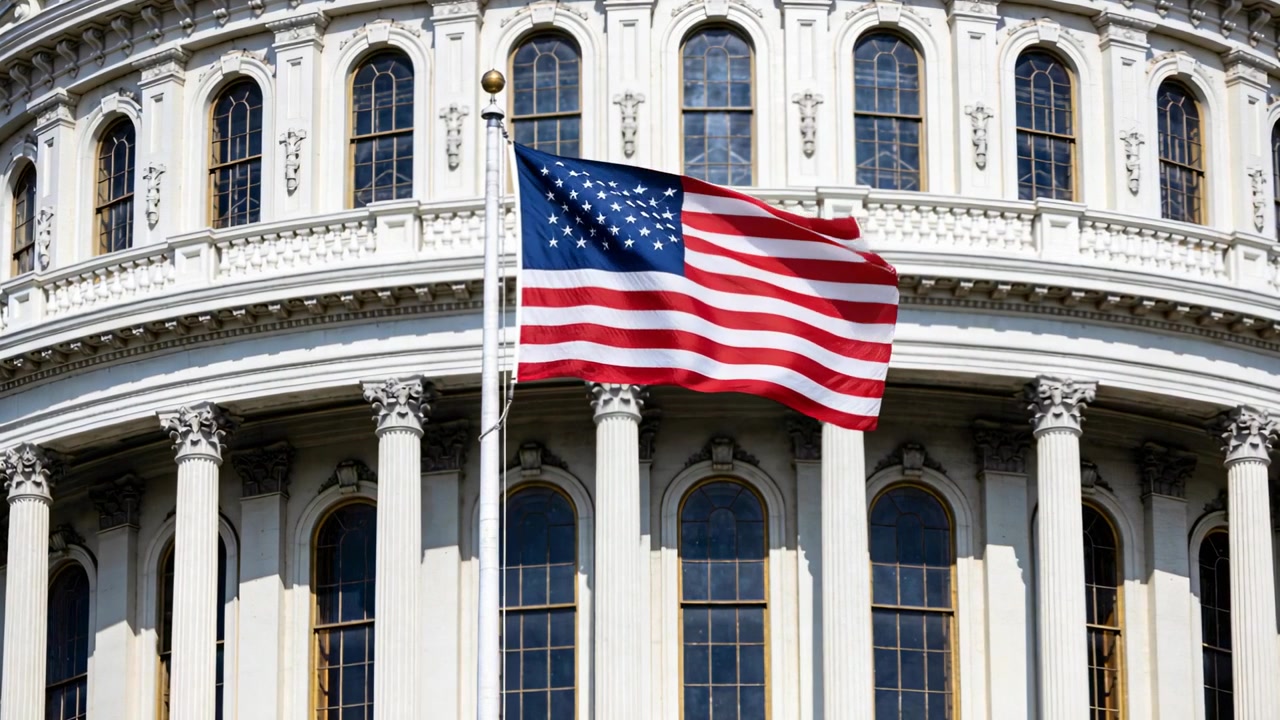 Una bandiera americana che sventola su un'asta sormontata da un puntale dorato, che cattura raffiche di vento presso il colonnato del Campidoglio.