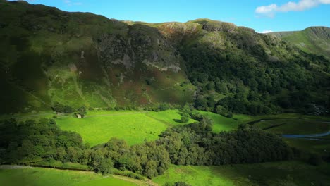 sunlight and shadows moving against lush green countryside and steep mountain on summer day