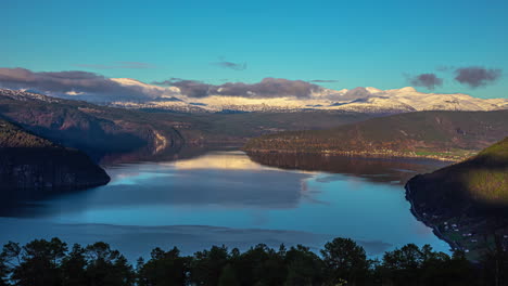 Una-Vista-Impresionante-De-Un-Gran-Fiordo-En-Noruega---Lapso-De-Tiempo-Diurno-Con-Un-Bote-En-El-Agua-Y-Un-Paisaje-Nublado-Sobre-Las-Lejanas-Montañas-Nevadas