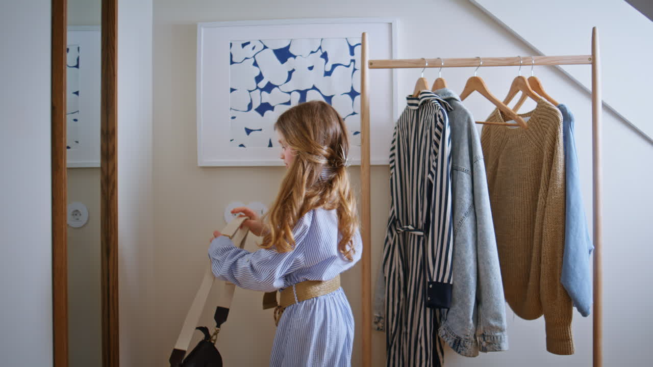 Small girl choosing dress looking reflection at mother wardrobe. Kid playing