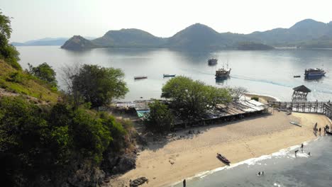 exotic-beach-at-Pulau-Kelor-island-in-Indonesia-at-Komodo-national-Park,-shot-from-a-drone,-offering-a-stunning-aerial-perspective-of-the-island's-beauty-and-mountains-in-the-background