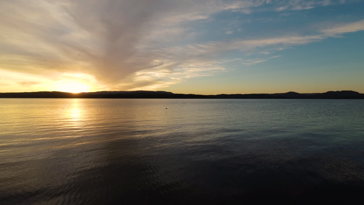 Scenic sunset FPV aerial flying over a tranquil river at dusk.