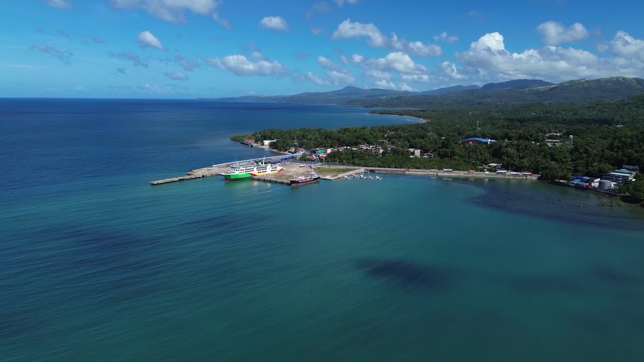 Vista aerea con drone del porto di Odiongan a Romblon, Filippine, che mostra un grande traghetto passeggeri attraccato al porto con la città costiera e la costa visibili sotto un cielo azzurro limpido in una giornata di sole