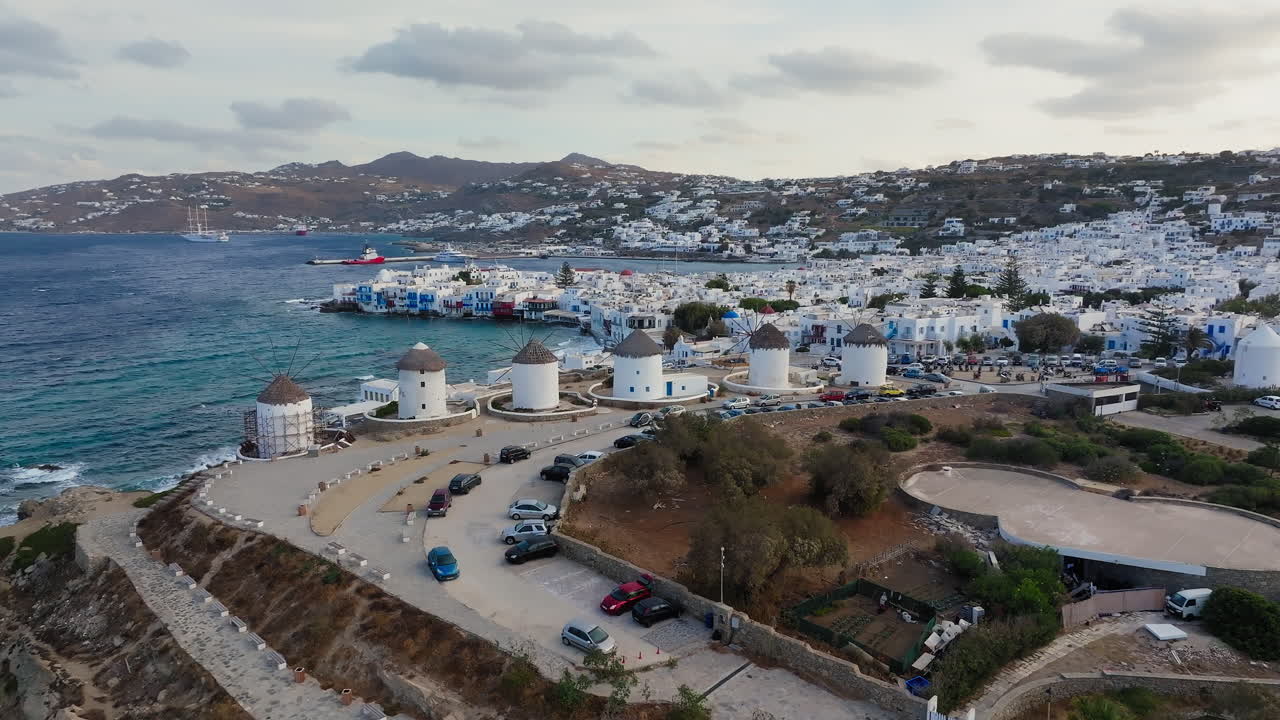 Ripresa con drone dei mulini a vento di Mykonos sull'isola greca circondati dall'oceano blu e dalle colline, isola delle Cicladi