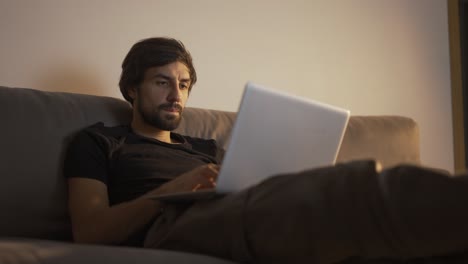 concentrated man working on a laptop at home while sitting on the couch