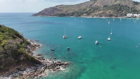 las imágenes aéreas capturan barcos balanceándose suavemente en las aguas turquesas de phuket, tailandia, bajo la brillante luz del día.