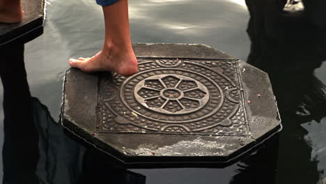 bali tourist stepping on stones in a palace pond, spiritual destination