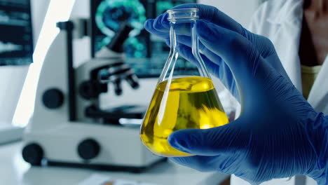 scientist holding a flask with yellow liquid in a lab