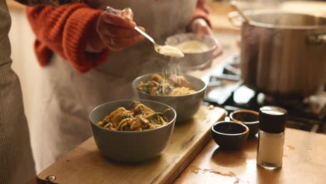 woman adding cheese to delicious pasta