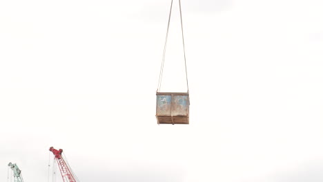 crate box lifted by tower crane in the air at construction site