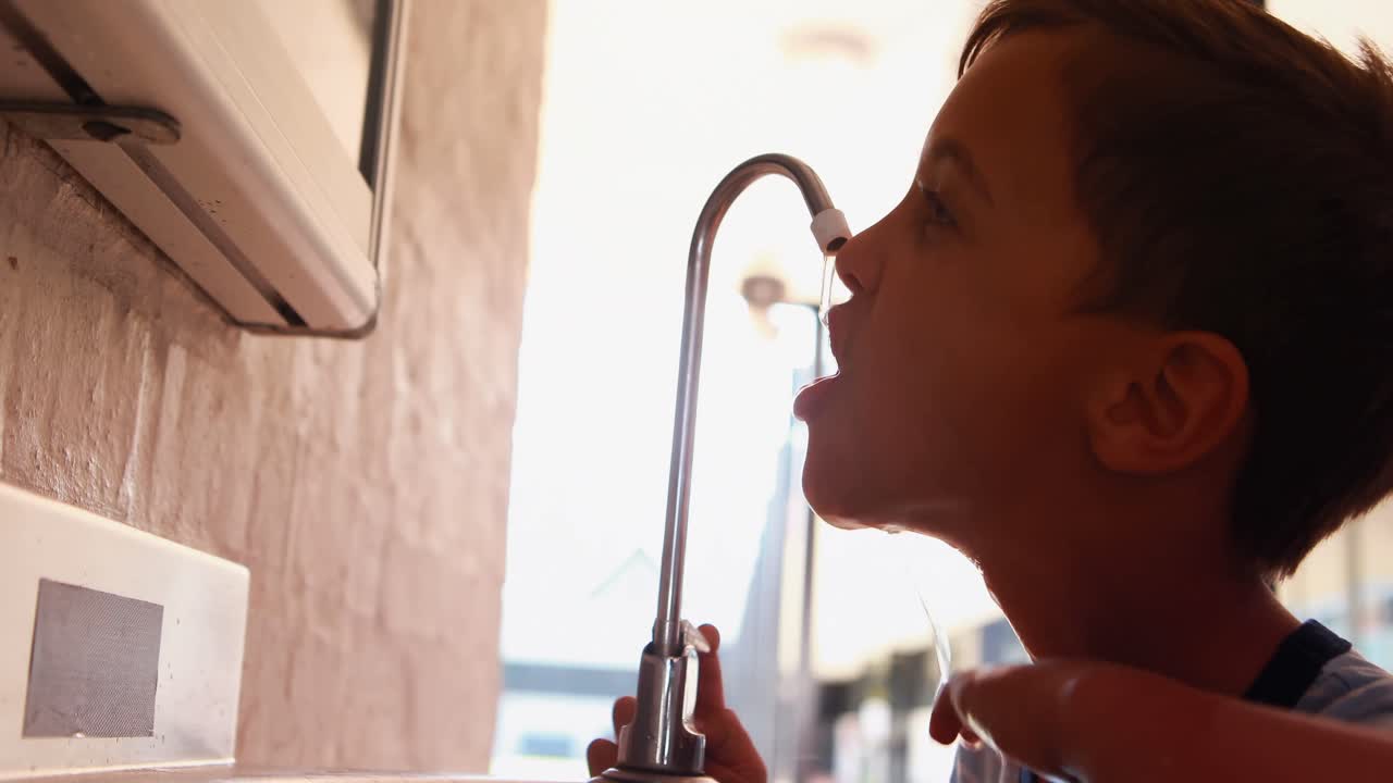 Scolaro assetato che beve acqua dal rubinetto 4k