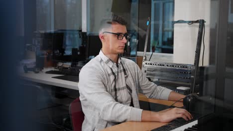 young man in glasses working at the computer at his workplace in the office