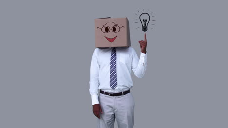 Businessman-hiding-head-with-happy-box-and-pointing-light-bulb