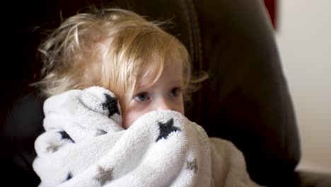 baby girl watching television wiht messy hair and holding her security blanket - close, isolated portrait