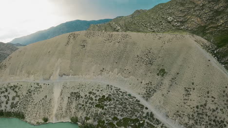 camino vacío en la ladera de la montaña sobre el río fpv drone. camino tentador para los viajeros para el atractivo escénico que ofrece vistas impresionantes. camino en pendiente empinada