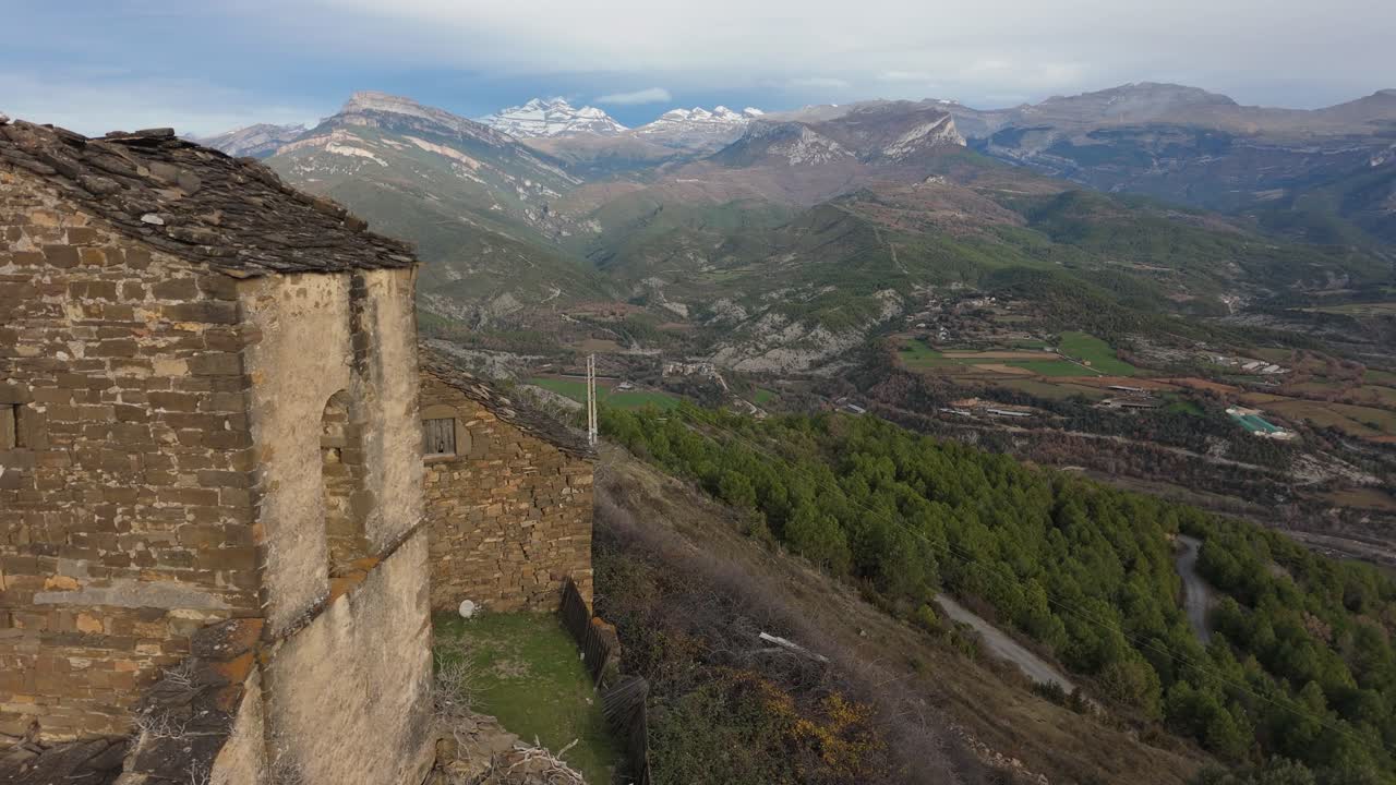 drone disparado desde una iglesia abandonada en muro de bellos, españa con un hermoso paisaje verde y una montaña nevada como fondo