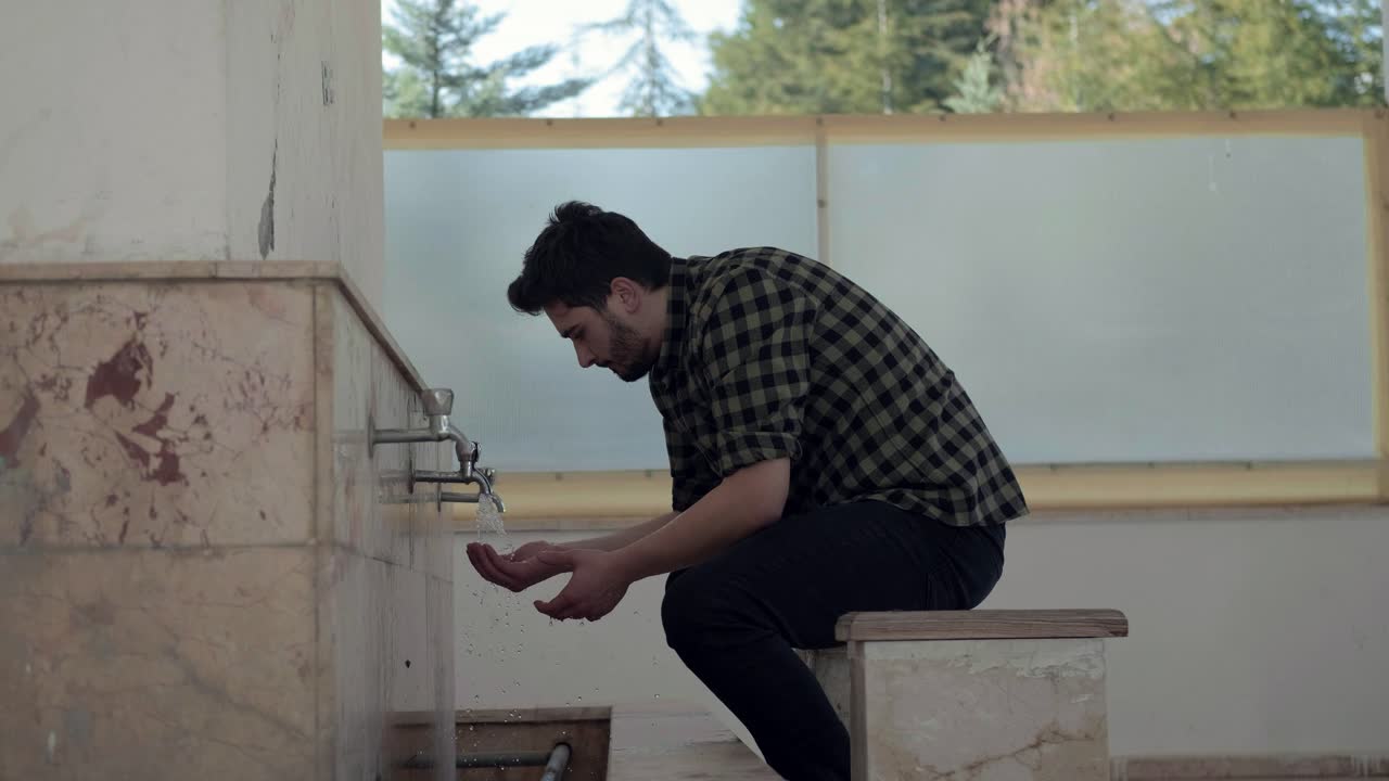 모스크 3에서 기도를 위해 재계를 받는 젊은 무슬림 남자