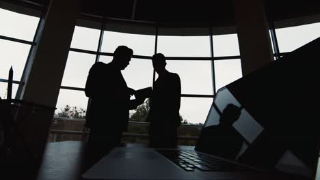 silhouettes of two businessmen meet in a spacious hall by the window 1