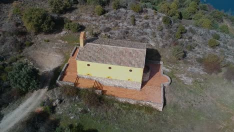 toma aérea orbitando sobre una pequeña ermita cerca de un lago