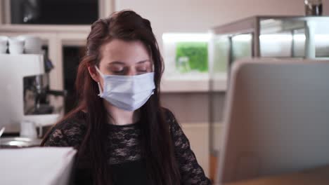 Girl-wearing-face-mask-using-computer-and-speaking-mobile-phone,-closeup-view