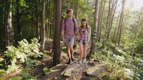 a young couple of tourists walking along a mountain path in the rays of the setting sun