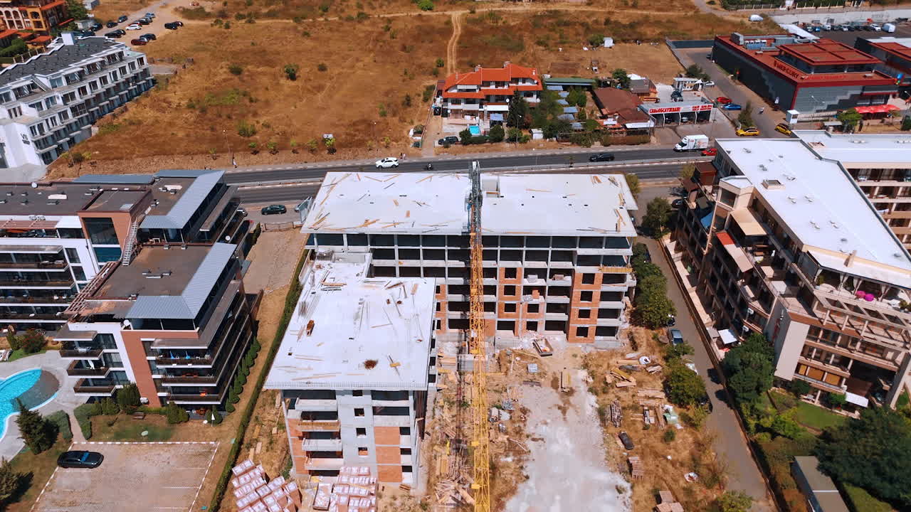Varna, Bulgaria, 29 June 2025: Construction site between finished resort complexes. An elevated view shows the two unfinished building shells surrounded by existing hotels and pools