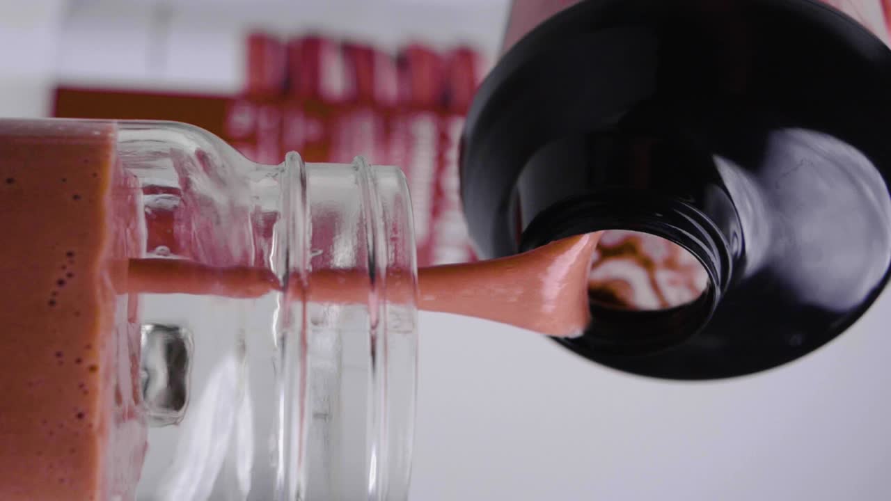 disparo vertical estático en cámara lenta de un agitador llenando un vaso con un batido de proteína de chocolate vegano