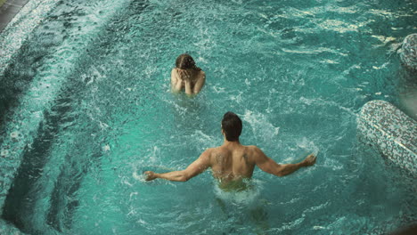 Happy-couple-having-fun-in-pool-spa.-Lovely-couple-splashing-in-pool